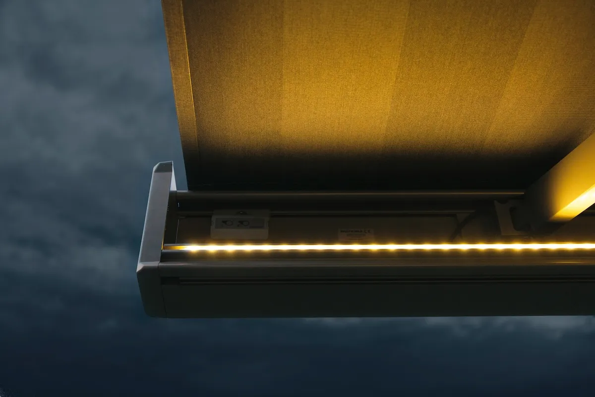 Wohnzimmer mit geöffneter Insektenschutz-Schiebetür Eine Markise mit LED-Beleuchtung